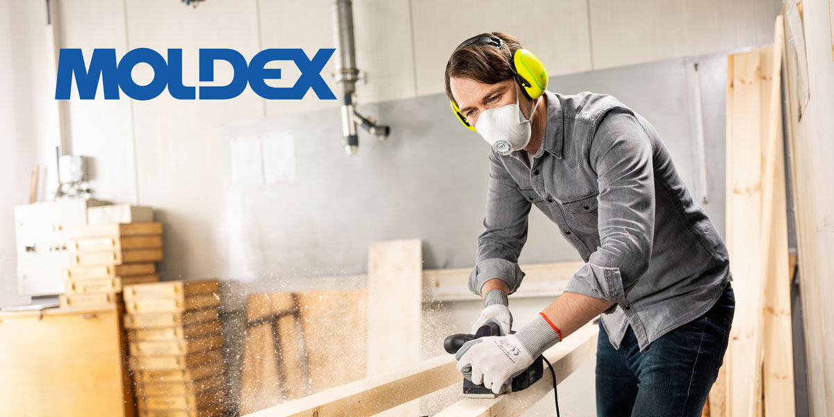 Ein Handwerker mit Moldex Atemschutzmaske schleift einen Holzbalken ab.